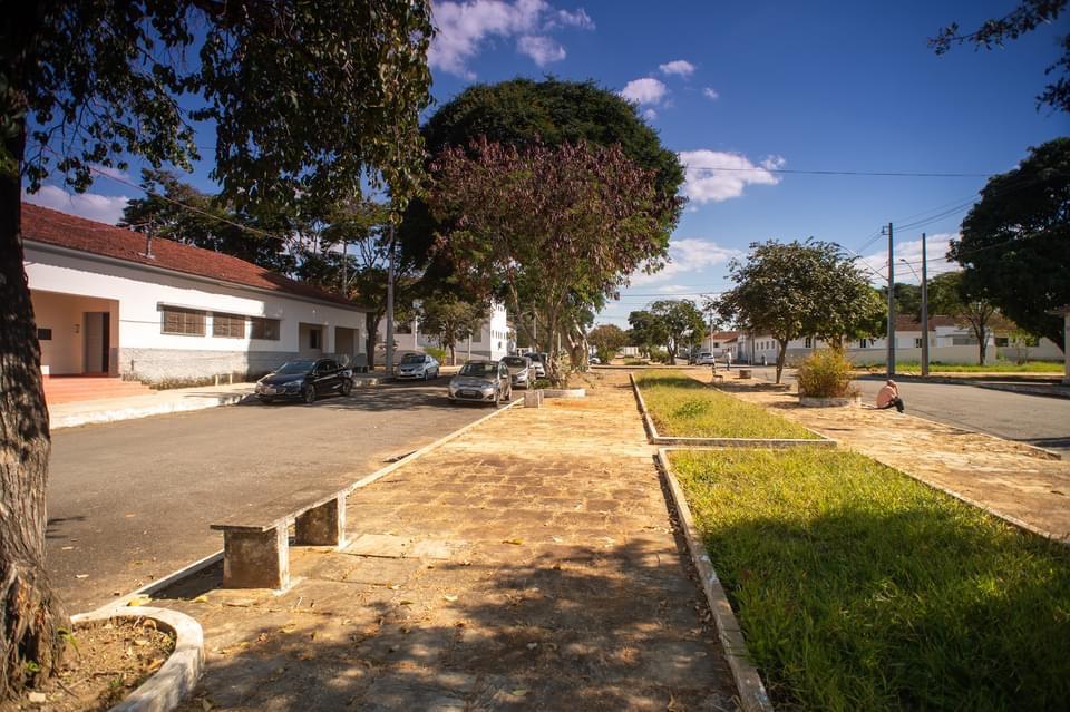 Rua em Barbacena, com casas, árvores e veículos, em cena urbana tranquila