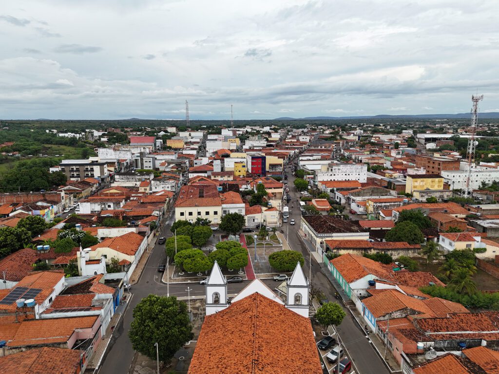 Vista aérea de São Raimundo Nonato, com vias urbanas e colinas de caatinga ao fundo, em fim de tarde