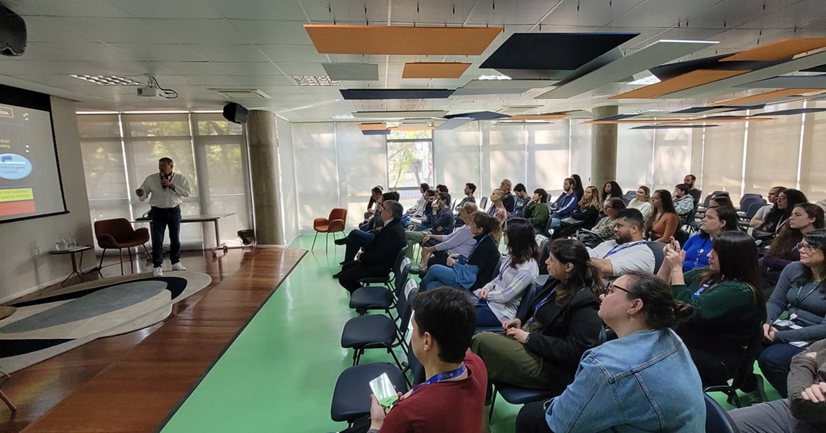 Palestra acadêmica em ambiente universitário, com público diverso e projeção de slides