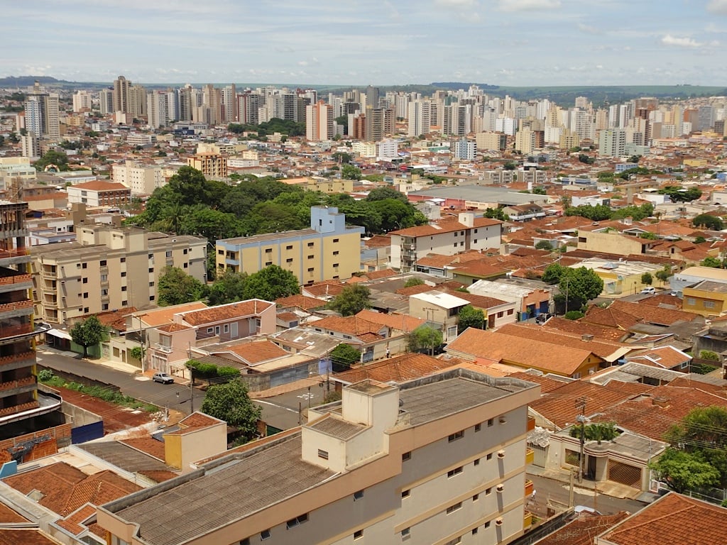 Skyline urbano de Ribeirão Preto ao pôr do sol, com prédios e áreas verdes
