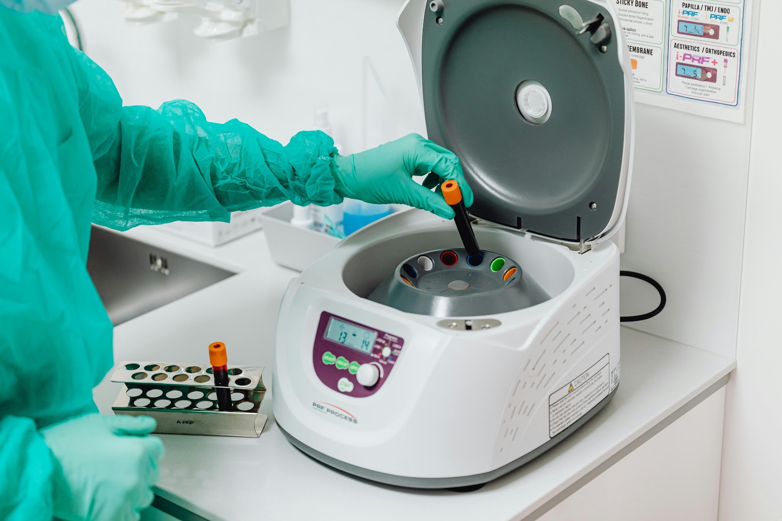Bancada de laboratório clínico com centrífuga e tubos de ensaio organizados; ambiente limpo e bem iluminado