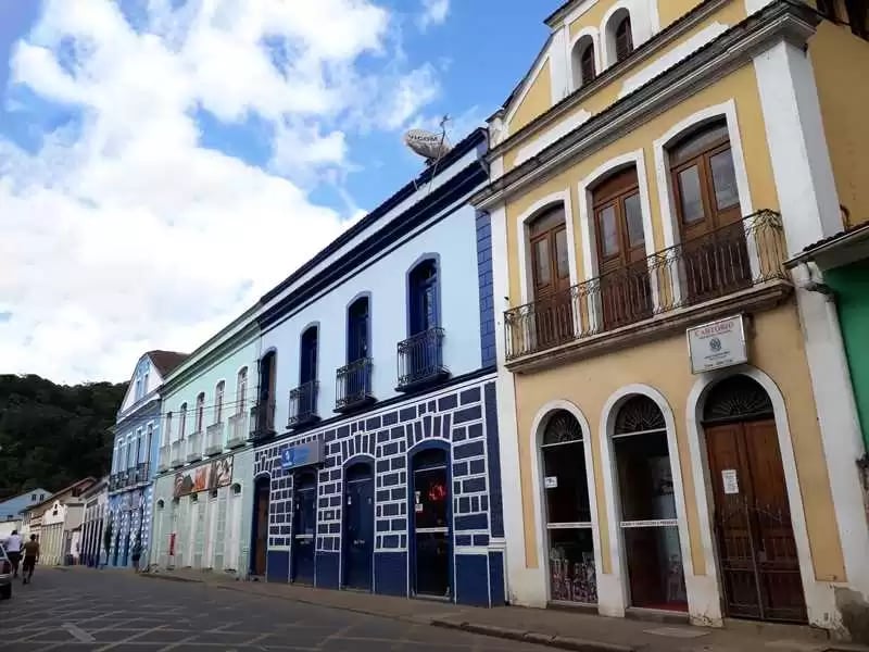 Centro histórico de cidade mineira com casarões e via urbana em dia claro