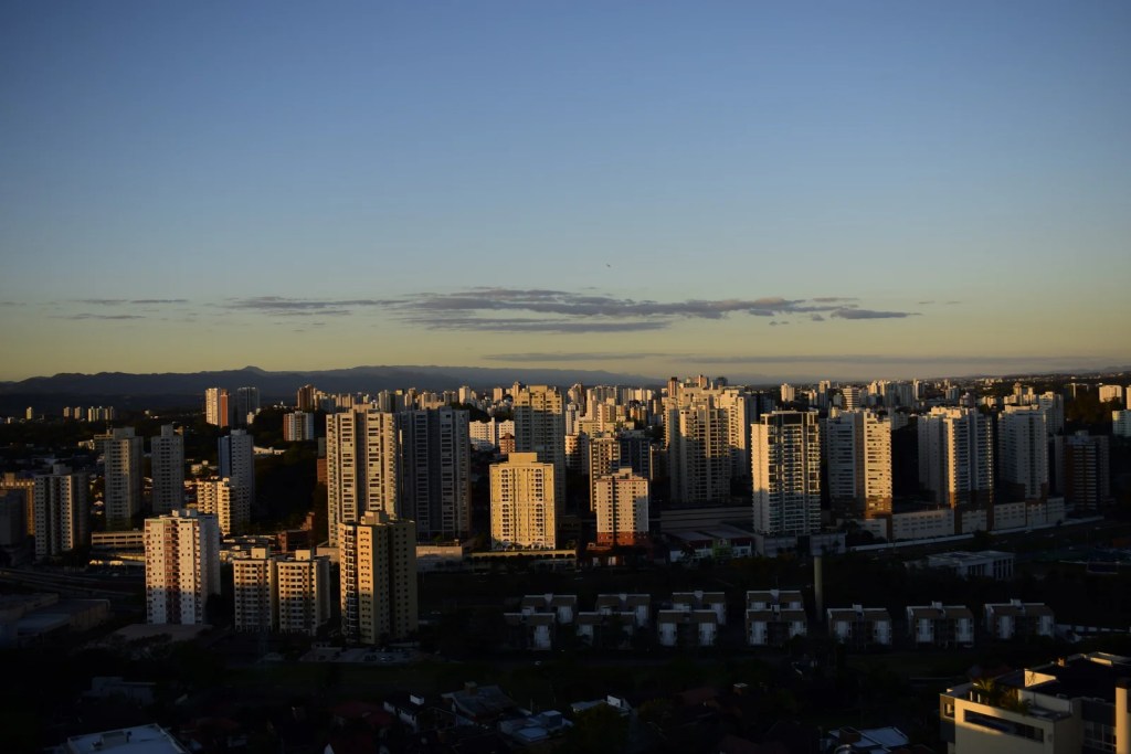 Panorama de Guaratinguetá ao entardecer, com centro histórico e serras ao fundo