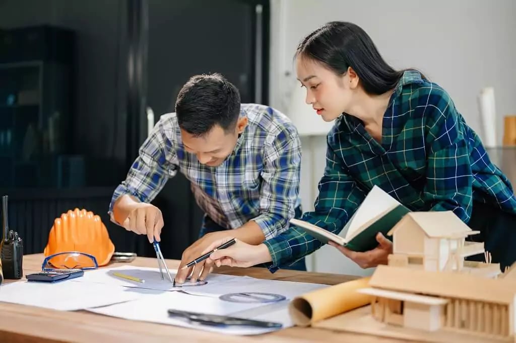 Profissionais de arquitetura analisando plantas em ambiente colaborativo, com foco em habitação social.