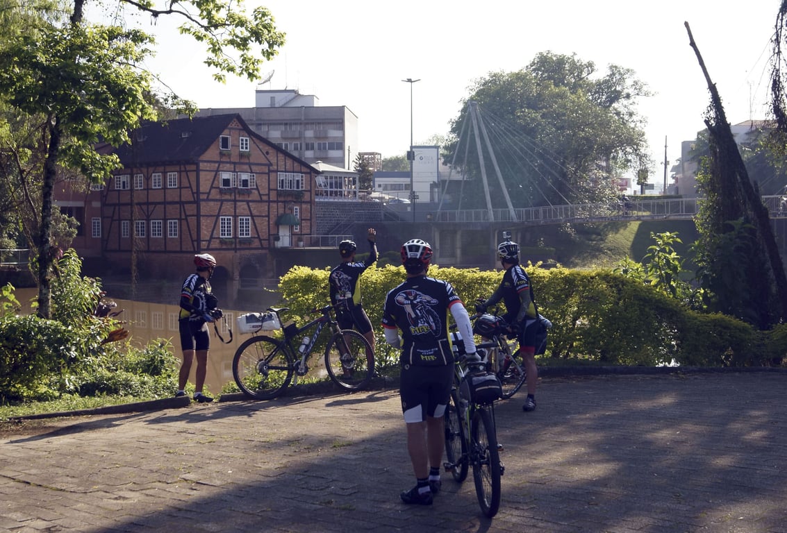 Ciclistas em estrada rural do Vale Europeu, com casario enxaimel ao fundo