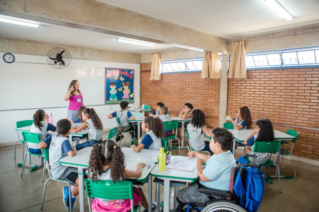 Sala de aula em escola pública, professora e estudantes em atividade
