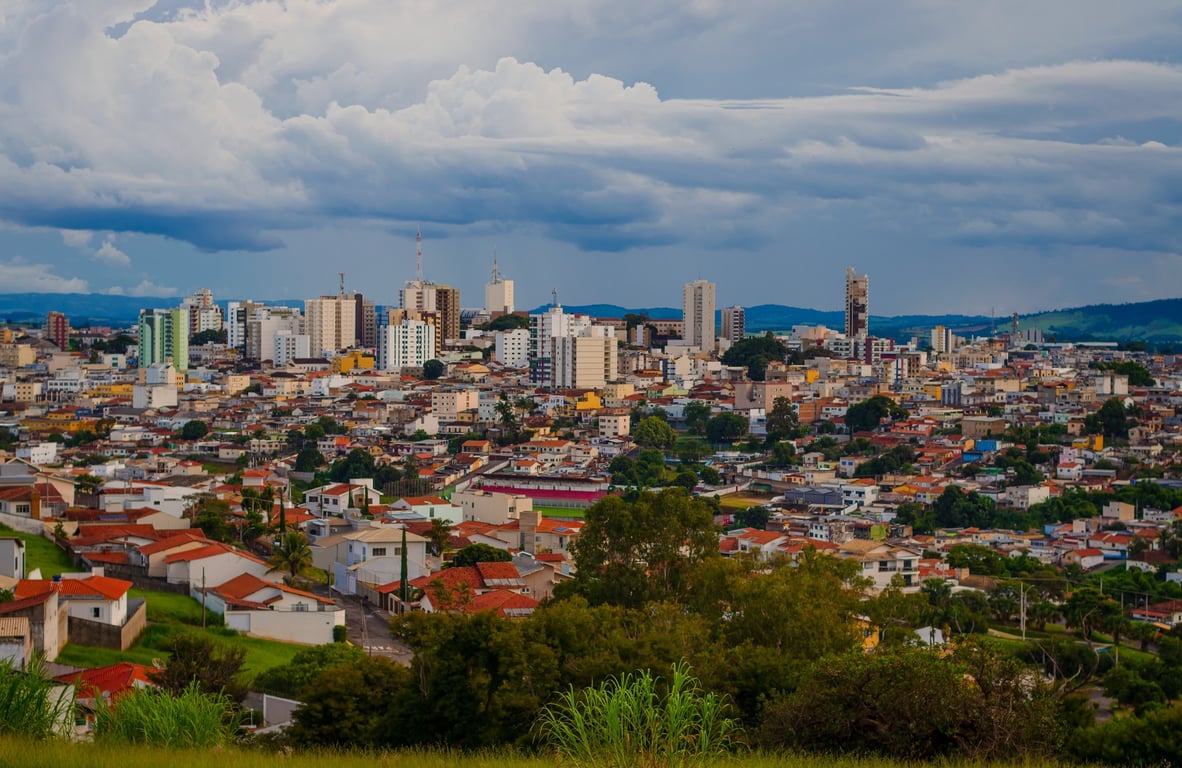 Vista panorâmica do centro de Varginha MG, com edificações e casas sob céu parcialmente nublado