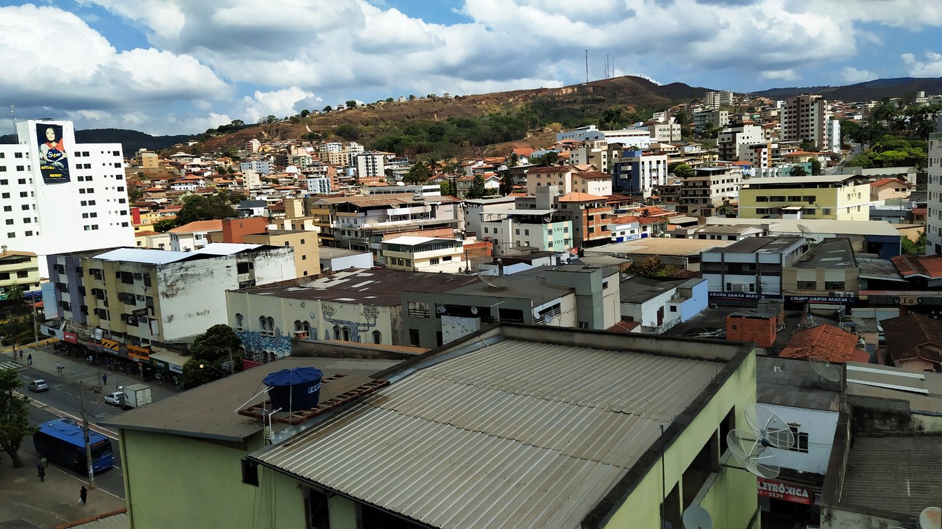 Vista urbana em Minas Gerais ao entardecer, com morros e cidade ao fundo