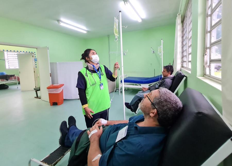 Profissionais de saúde em atendimento em UBS, com equipamentos e prontuário, ambiente acolhedor