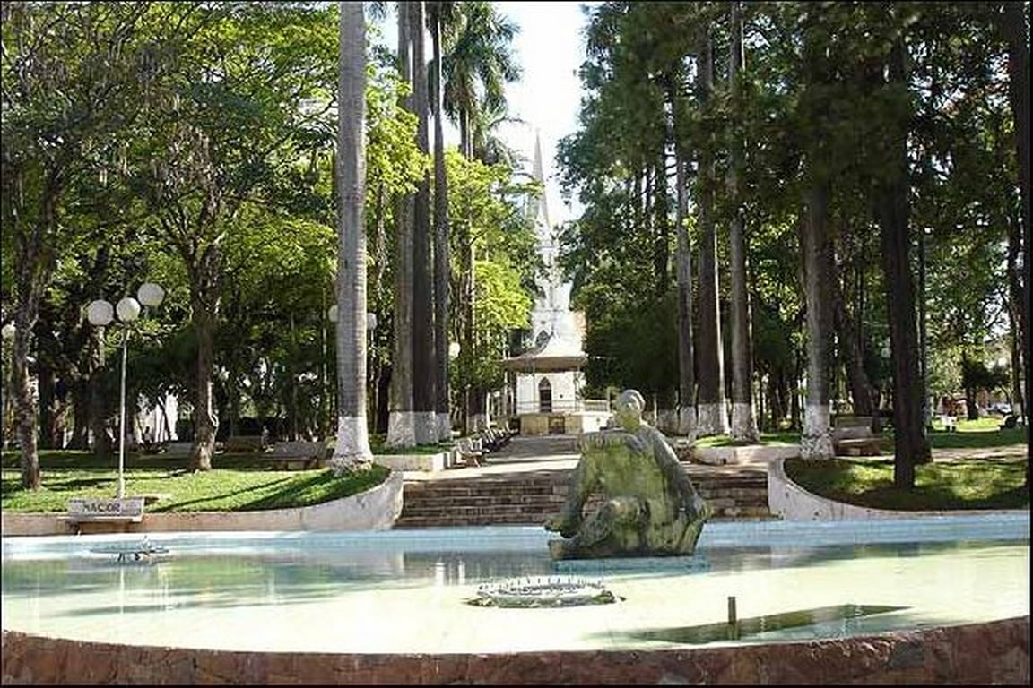 Vista da praça central de Mococa SP, com jardim, fonte e escultura ao entardecer