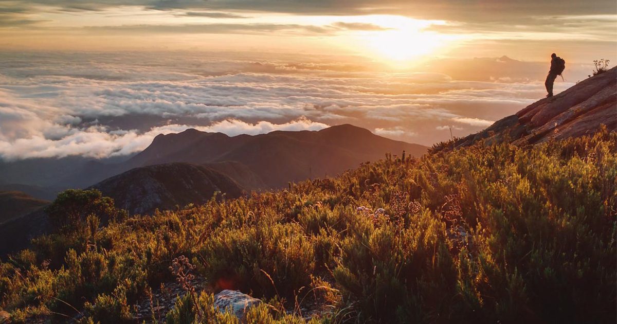Amanhecer nas montanhas do Parque Nacional do Caparaó, com céu colorido e nuvens sobre os picos