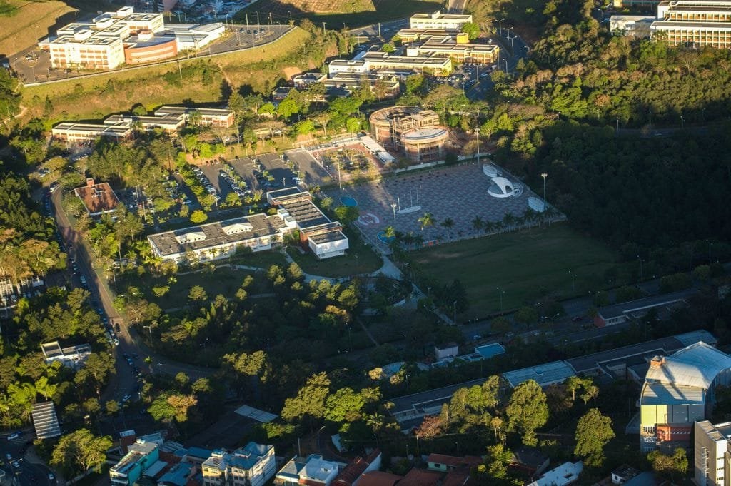 Vista do campus da UFJF com prédios integrados à paisagem e áreas verdes