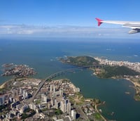 Vista aérea de Vitória ES, mostrando a Terceira Ponte e a baía ao entardecer.
