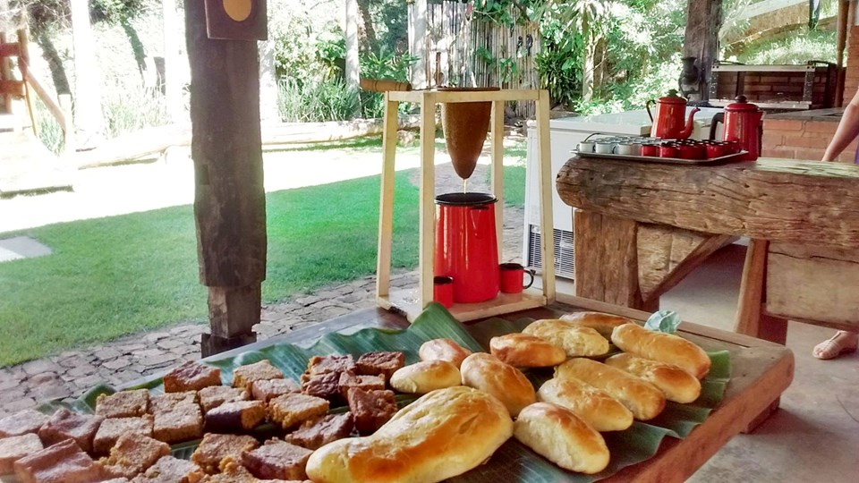 Mesa com pães e bolos em ambiente ao ar livre, remetendo ao turismo e à gastronomia da região do Caparaó