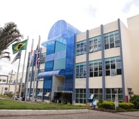 Fachada principal da Universidade Federal de Alfenas UNIFAL-MG em Alfenas, com bandeiras e circulação de estudantes.