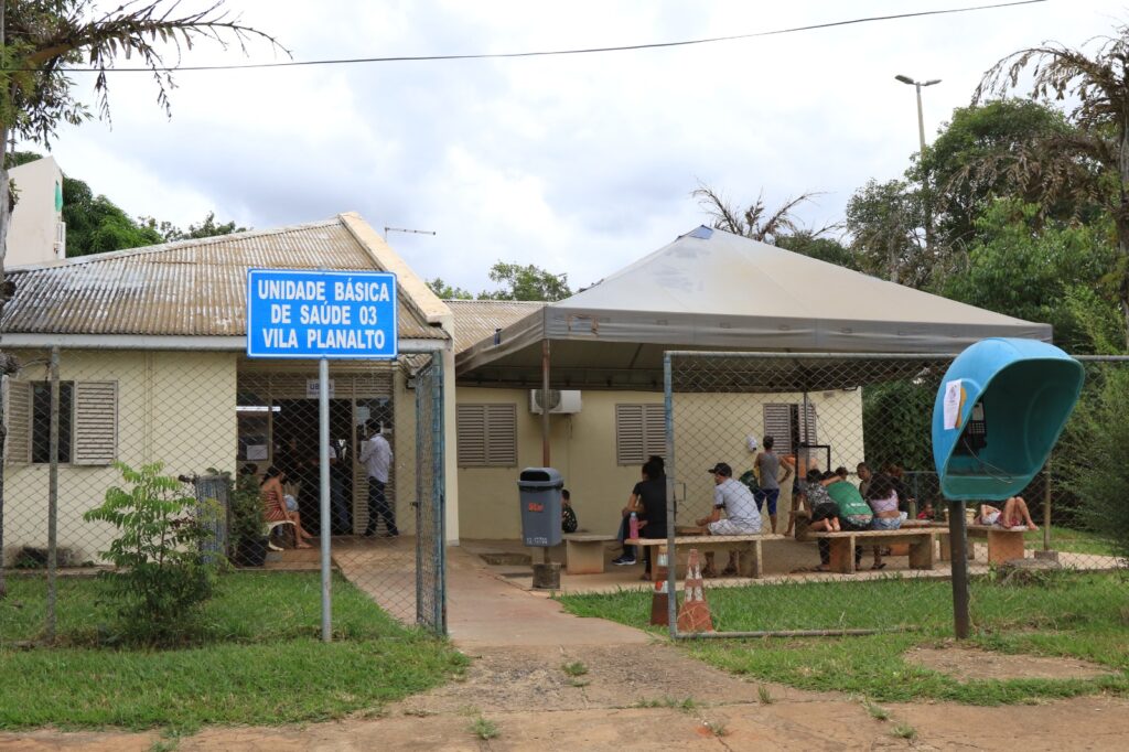 Unidade básica de saúde com pacientes aguardando e equipe ao fundo