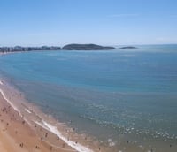 Vista aérea de Guarapari ao entardecer, com orla urbana e praias