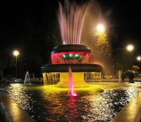 Fonte luminosa no parque de Valparaíso (SP) à noite com jatos de água coloridos.