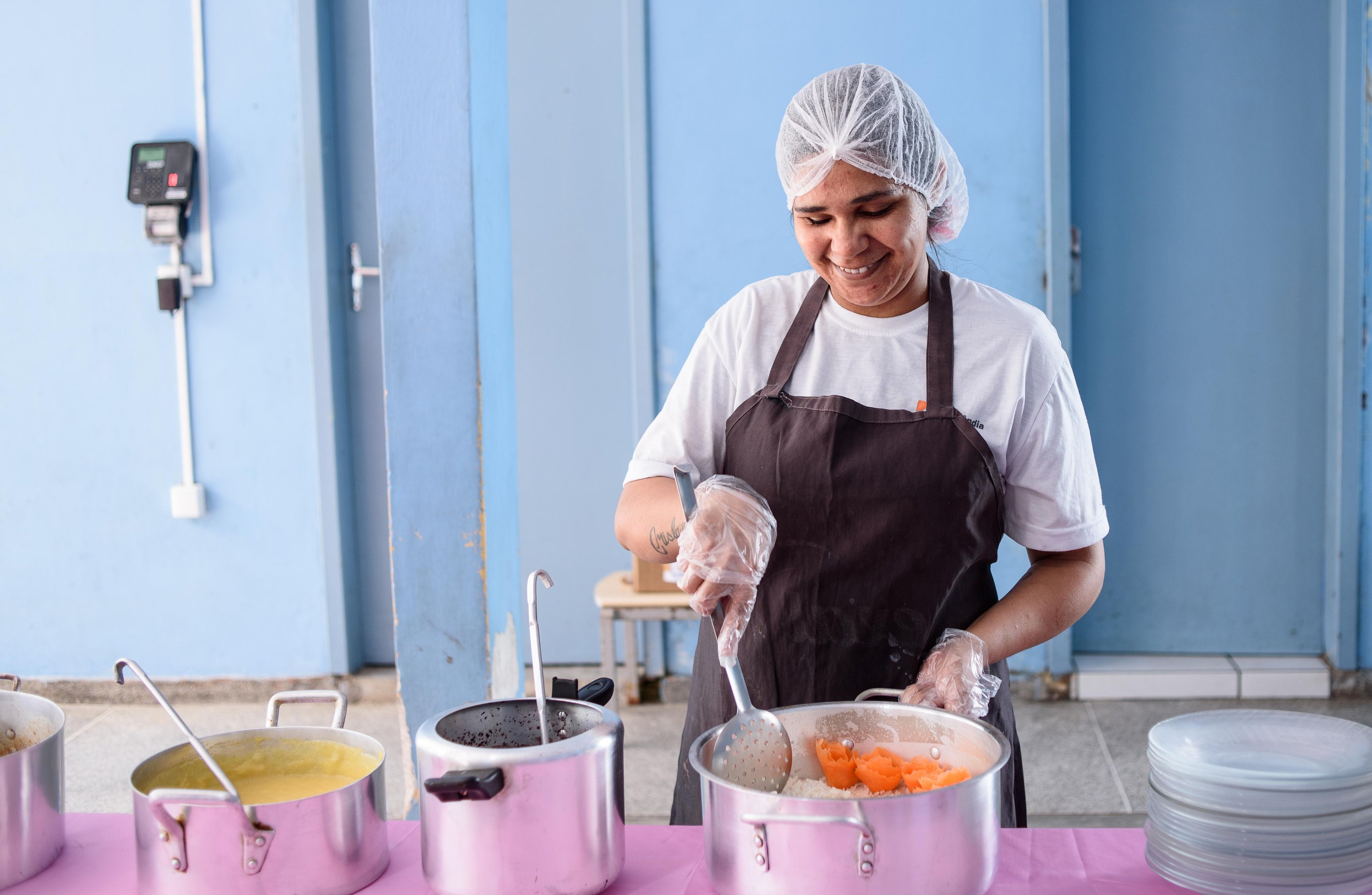 Cozinha escolar com merendeira em atividade