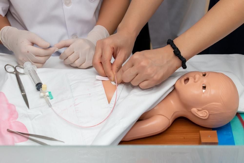 Alunos em laboratório de simulação de enfermagem, com manequins e materiais hospitalares