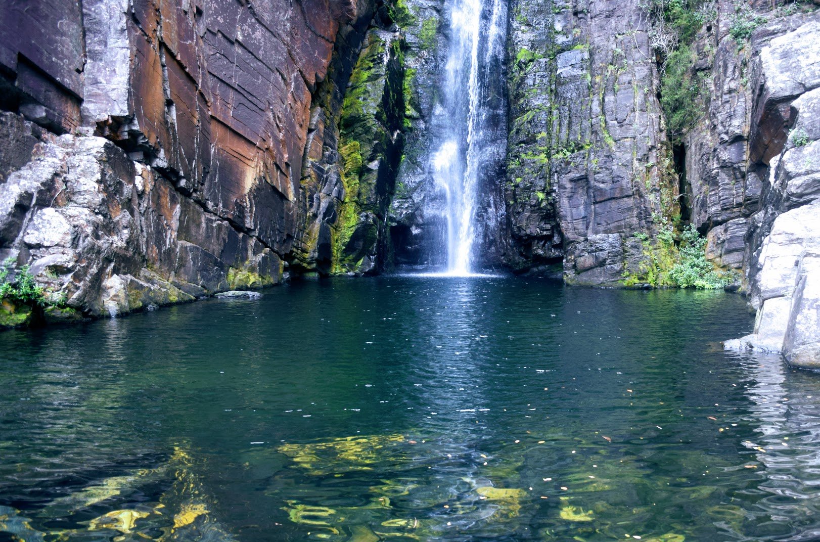 Paisagem do Parque Nacional da Serra do Cipó, com cânion e cachoeira, vegetação rupestre e paredões rochosos