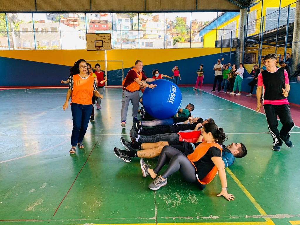 Ginásio escolar com atividade física em grupo, coletes coloridos e ambiente de aula prática
