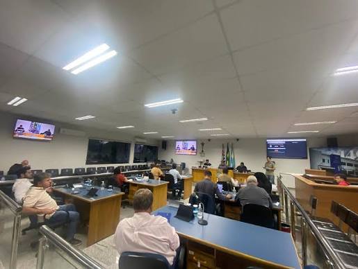 Imagem ilustrativa de plenário de câmara municipal, com mesas e cadeiras dispostas para sessão legislativa