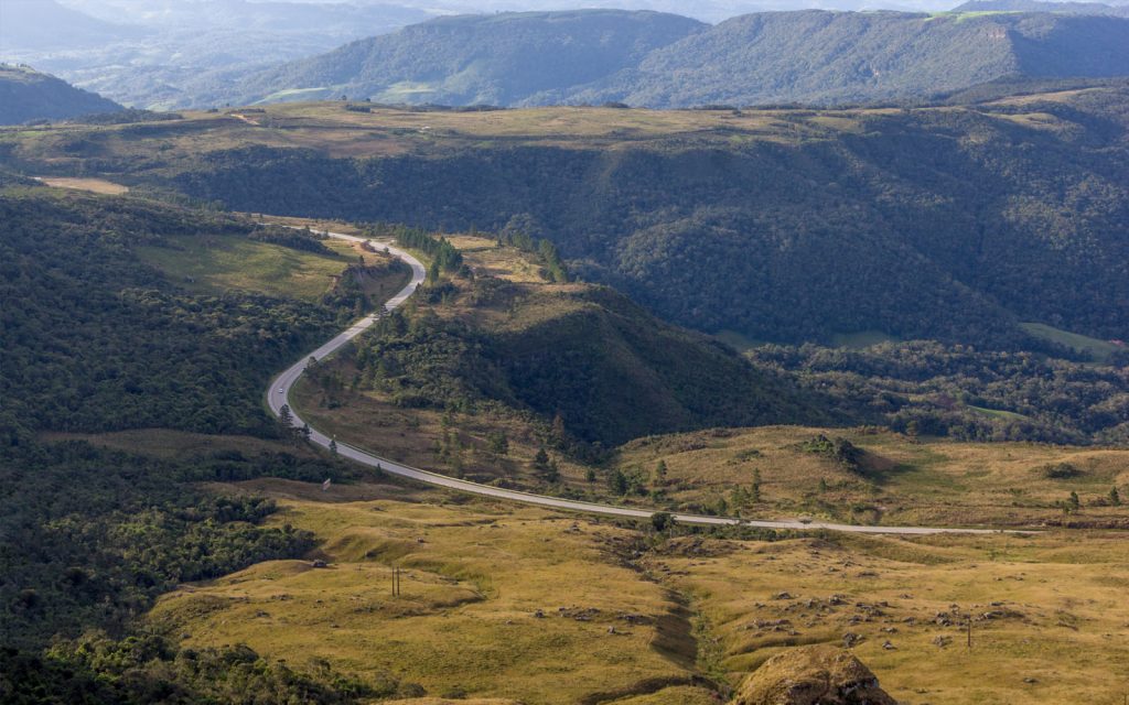 Paisagem serrana com estrada sinuosa e montanhas ao fundo, representando o clima de montanha de Rancho Queimado