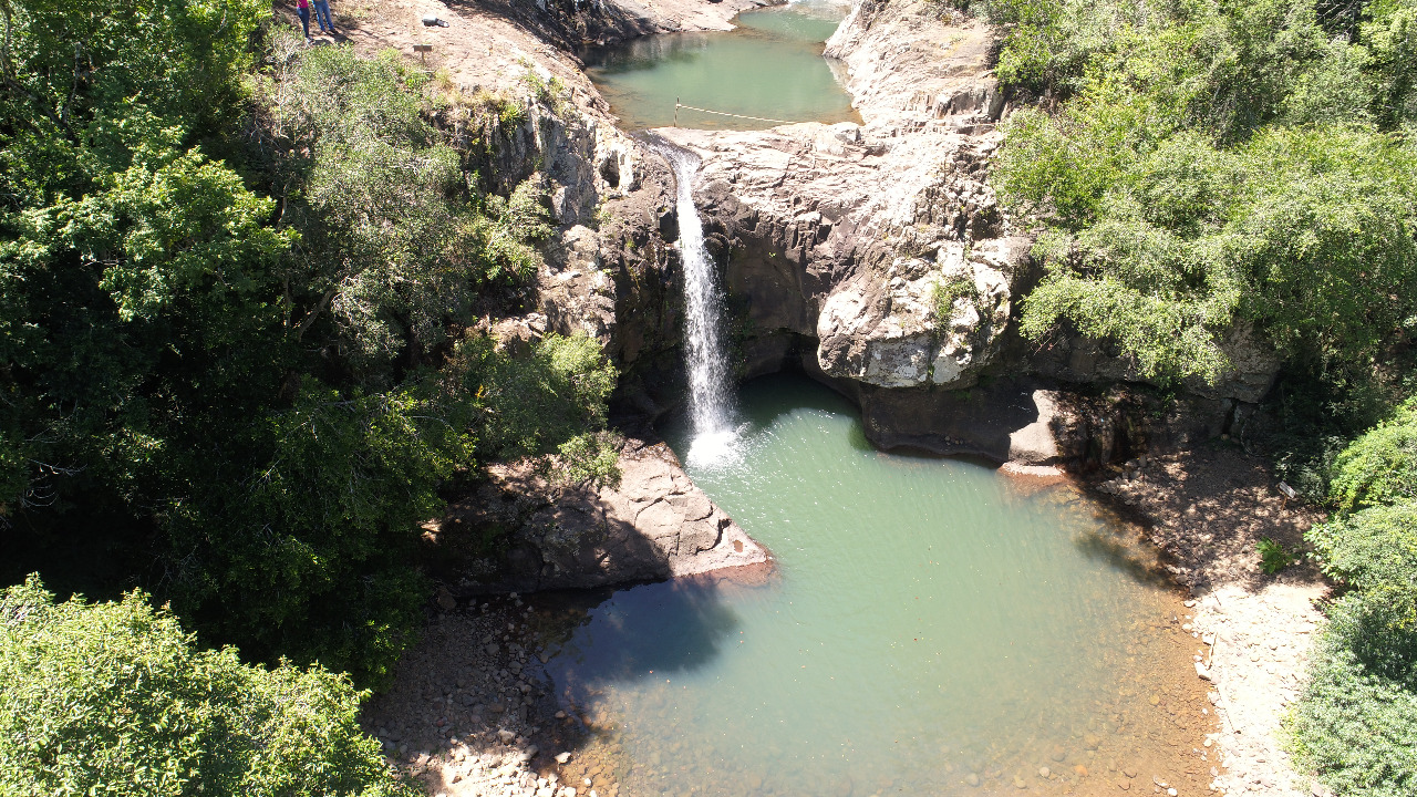 Paisagem da Quarta Colônia, com morros, vegetação e uma cachoeira ao fundo