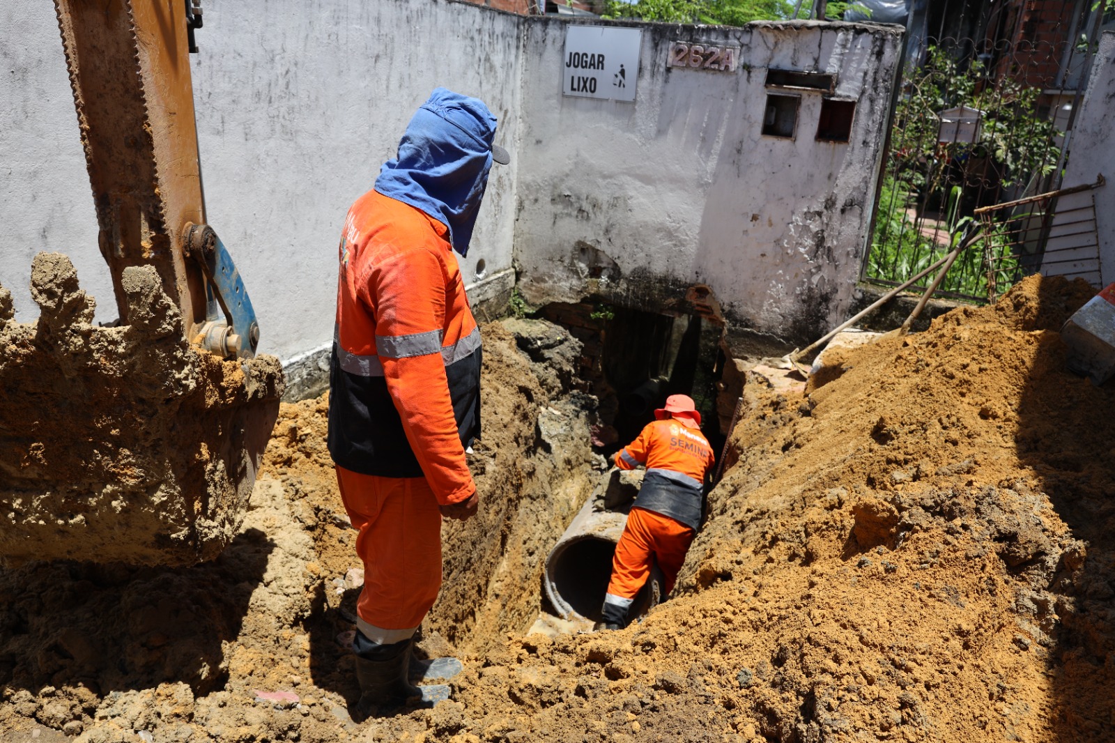 Trabalhadores municipais executando serviços urbanos, com caminhão e equipe uniformizada, em área urbana de pequeno porte