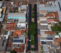 Vista aérea da avenida principal de Caarapó MS, com paisagem urbana e árvores.