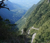 Serra Catarinense ao entardecer, com montanhas e estrada sinuosa em primeiro plano