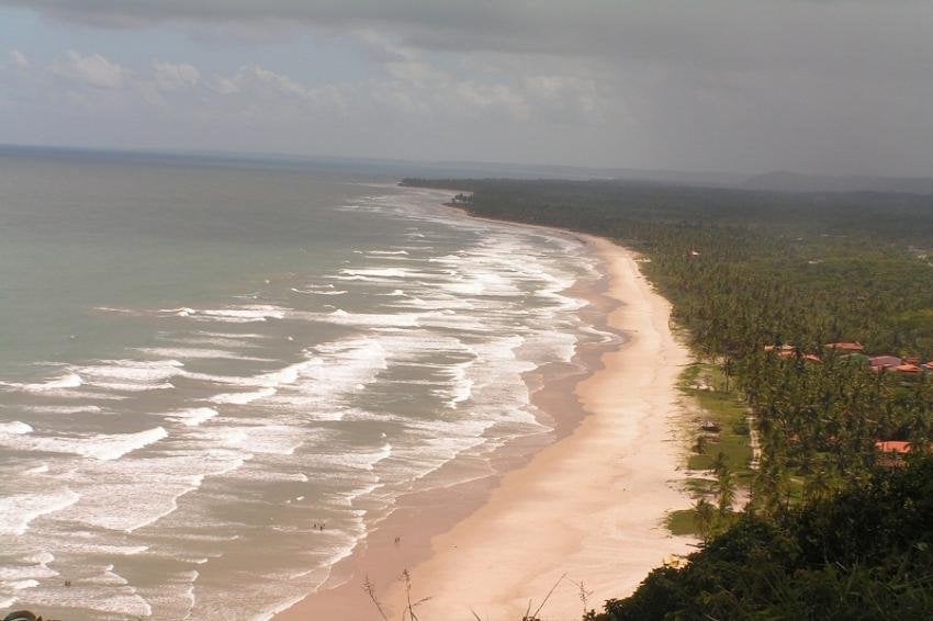 Vista aérea litorânea na Costa do Cacau, com faixa urbana e vegetação nativa ao entardecer