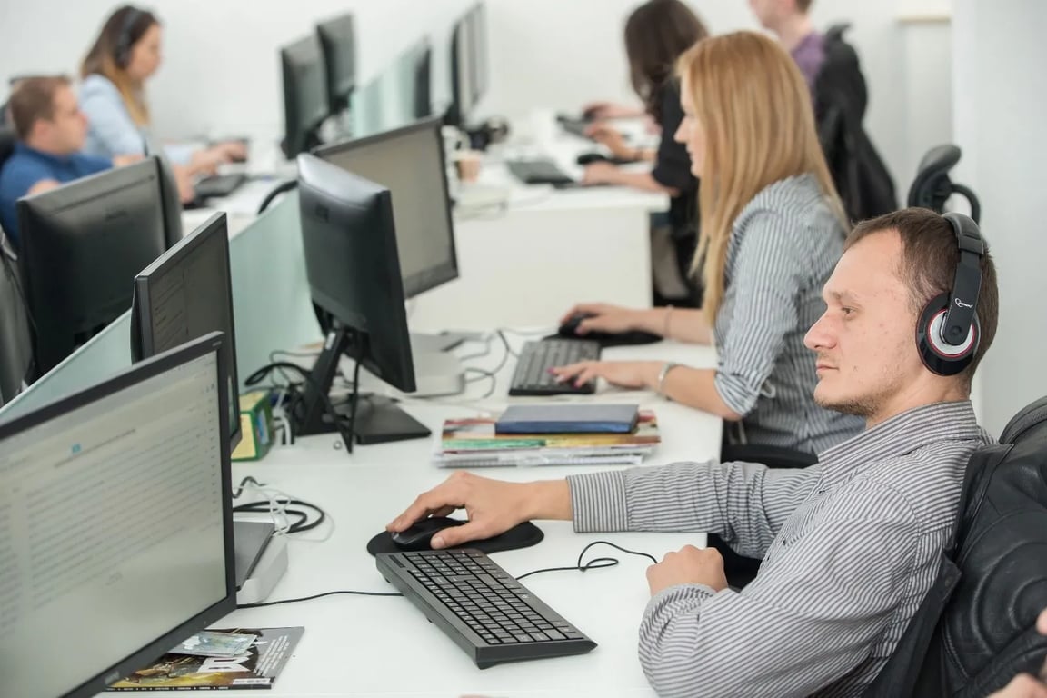 Ambiente colaborativo de desenvolvimento de software em escritório moderno, com telas exibindo interfaces de motor de jogos e perfis de desempenho