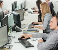 Ambiente colaborativo de desenvolvimento de software em escritório moderno, com telas exibindo interfaces de motor de jogos e perfis de desempenho