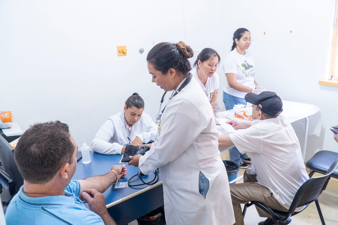 Profissionais de saúde em uma unidade básica, em enquadramento horizontal, durante atendimento