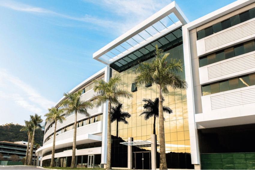 Fachada de unidade de saúde com paisagismo e céu azul