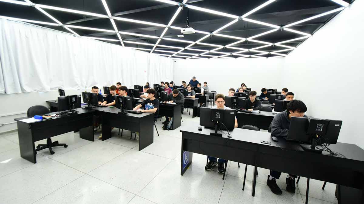 Laboratório de informática com estudantes em computadores em ambiente acadêmico