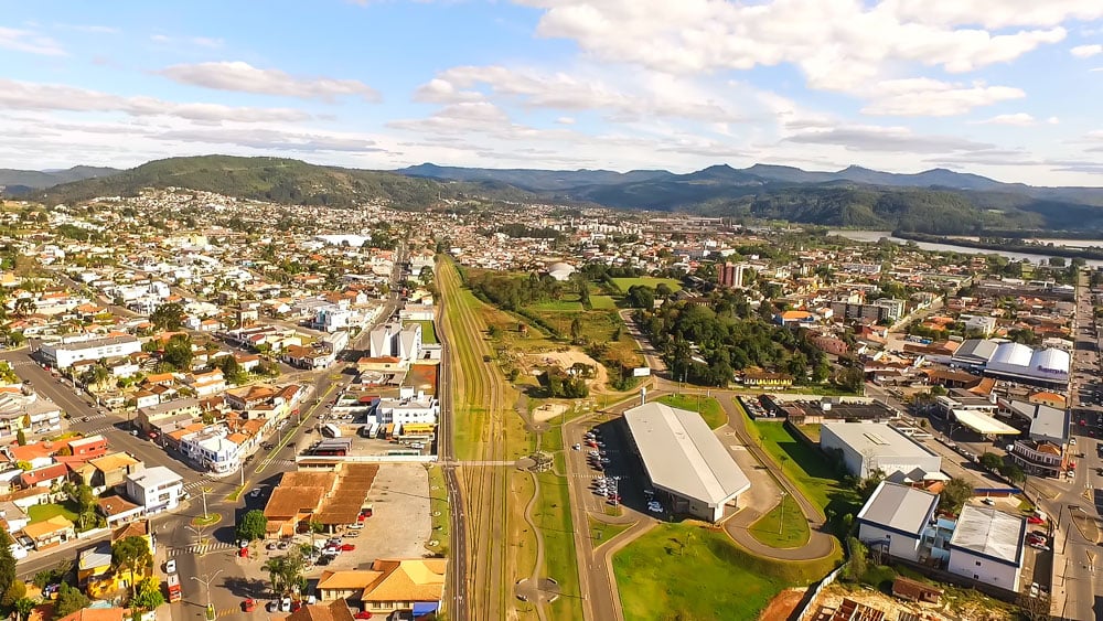 Vista aérea de União da Vitória (PR), às margens do Rio Iguaçu, com a ponte para Porto União (SC) e área central ao fundo.