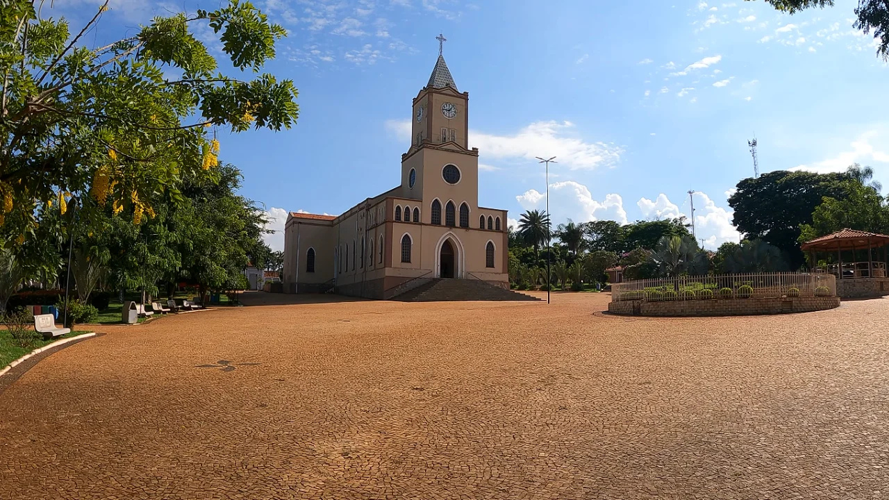 Praça e igreja em cidade do interior do RS, sob céu azul.