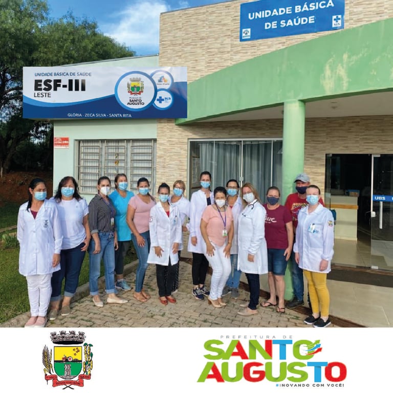 Profissionais de saúde em frente a uma UBS no RS, em ambiente iluminado e bem conservado