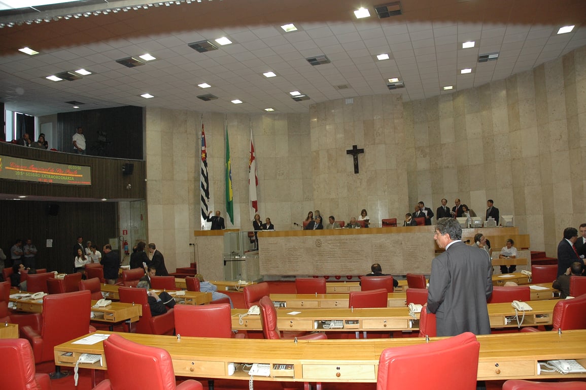 Plenário de câmara municipal com cadeiras e microfones