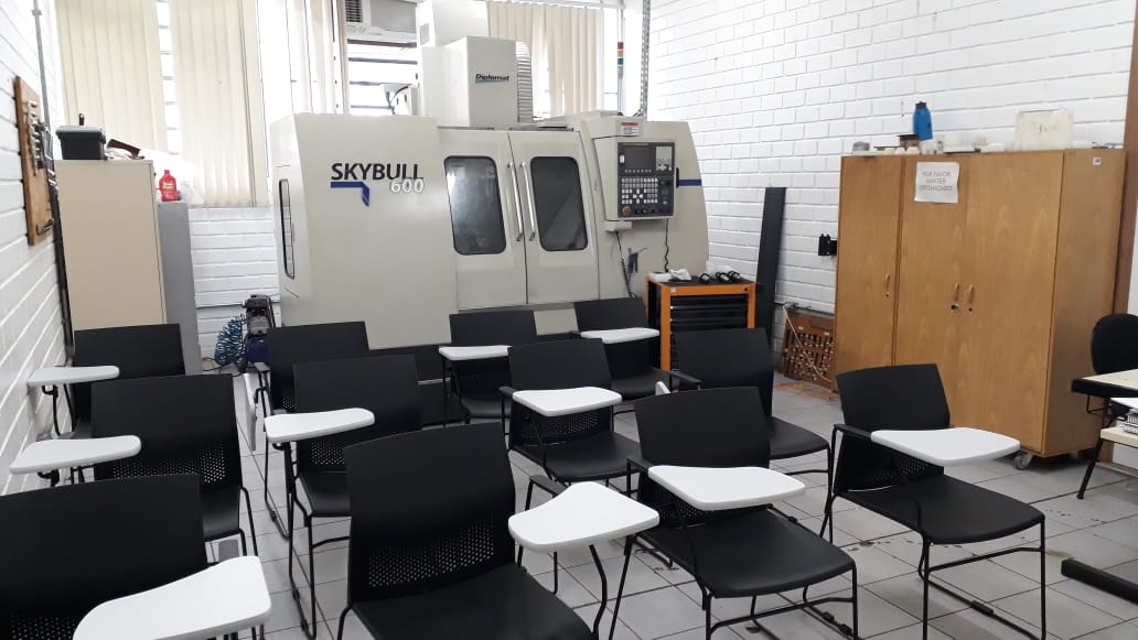 Laboratório acadêmico de engenharia com equipamentos de hidráulica e pneumática e mesas de trabalho