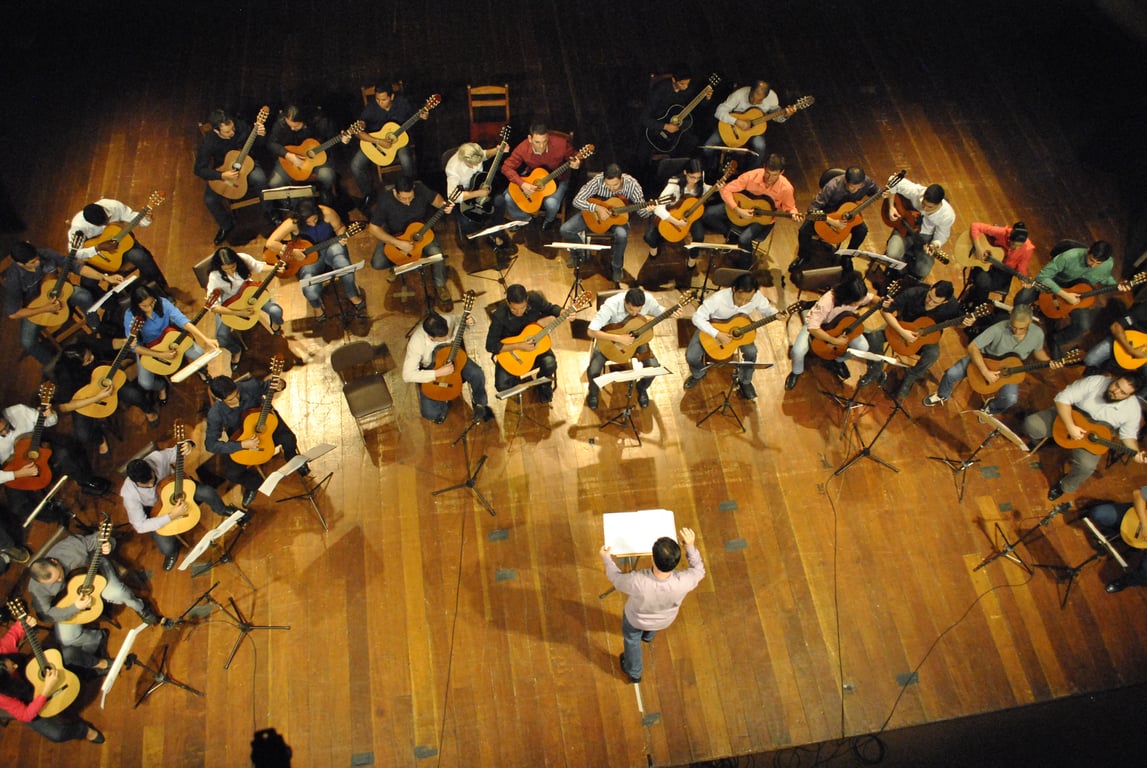 Aula de música com diversos violões e partituras em ambiente acadêmico