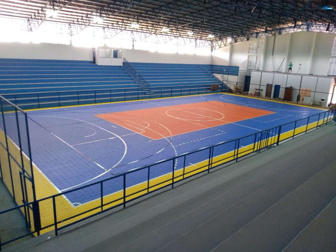 Quadra poliesportiva coberta vazia, com marcações no piso