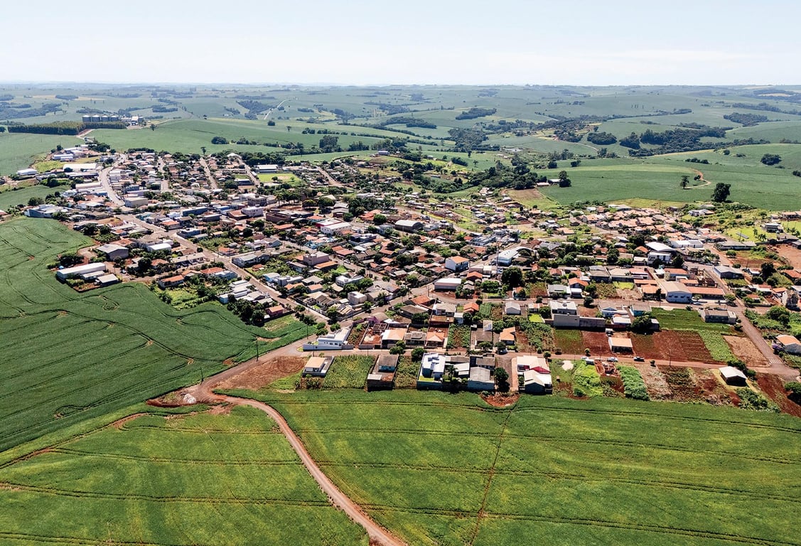 Vista aérea de uma pequena cidade do interior de Santa Catarina, com casas baixas e áreas verdes ao redor.