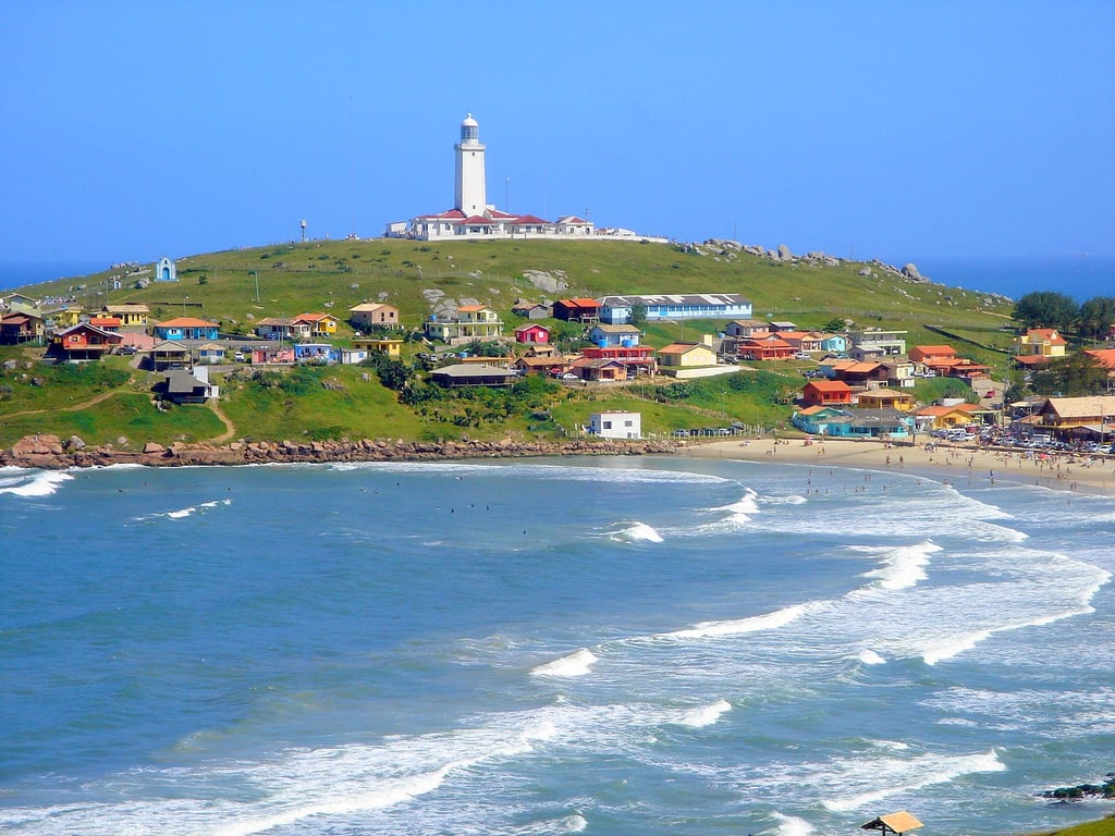 Paisagem costeira no Sul de Santa Catarina, com farol e vila de pescadores ao entardecer