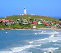 Paisagem costeira no Sul de Santa Catarina, com farol e vila de pescadores ao entardecer