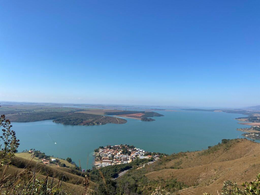 Represa ao pôr do sol cercada por morros, remetendo ao turismo de natureza no Sul de Minas