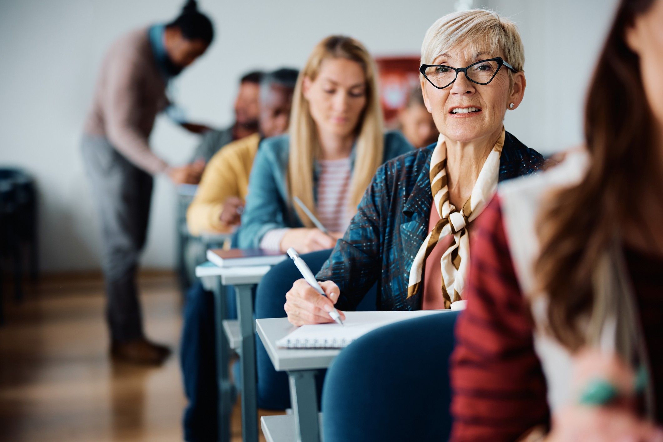 Aula noturna de jovens e adultos, com professor auxiliando alunos de diferentes idades